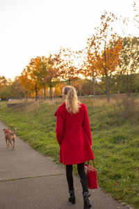 Rear view of woman with dog walking on street