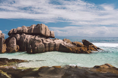 Rock formations on shore against sky