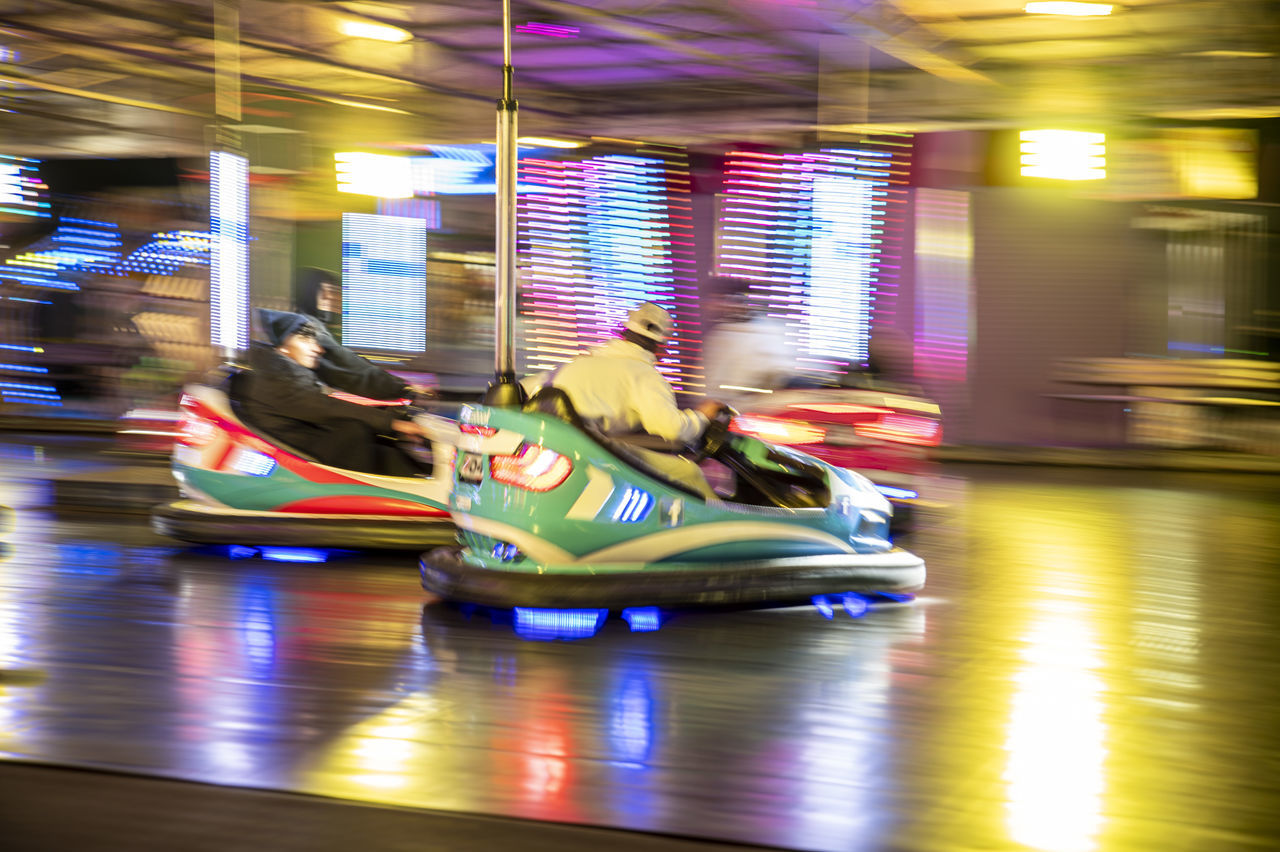blurred motion, speed, motion, illuminated, amusement park, transportation, indoors, night, architecture, mode of transportation, amusement park ride, multi colored, arts culture and entertainment, recreation, sports, vehicle, fun