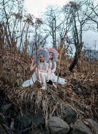 Full length of women sitting on tree