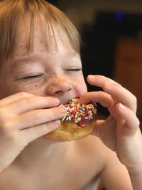 Close-up of shirtless boy eating donut at home