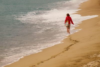 Rear view of woman walking at beach