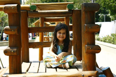 Portrait of smiling girl sitting on wood