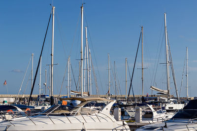 Sailboats moored at harbor against clear blue sky