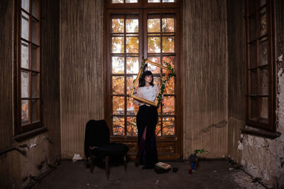 Woman sitting on chair in abandoned room