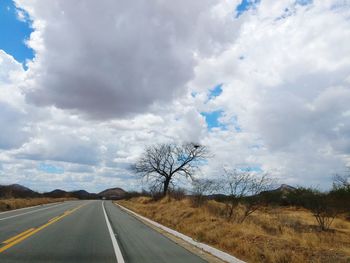 Road by trees against sky