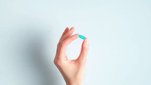 Close-up of woman hand against blue background