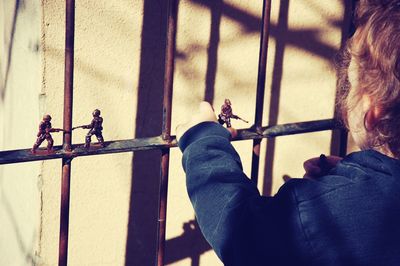 Girl keeping toy figurines on metal gate
