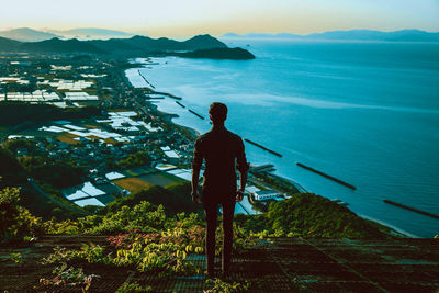 Rear view of man standing by sea against sky