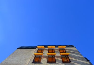 Low angle view of yellow building against blue sky