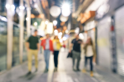 Rear view of people walking on illuminated road