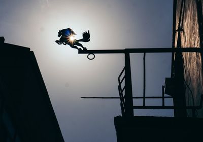 Low angle view of silhouette man paragliding against sky