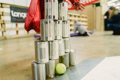 Close-up of stacked cans with tennis ball on floor