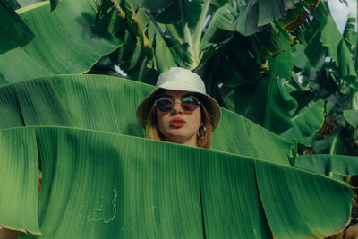 Portrait of woman with sunglasses on leaves