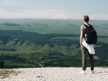 Rear view of woman standing on landscape against mountain