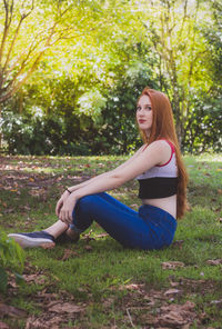 Side view of young woman sitting on field in park