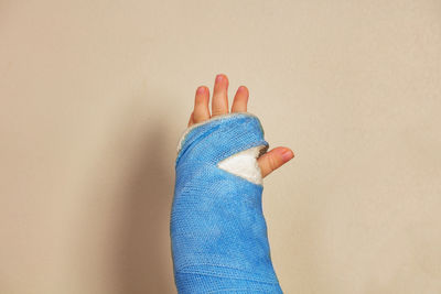 Cropped hand of woman with bandage against pink background