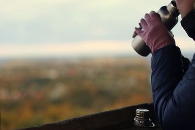 Midsection of woman holding bottle against sky during sunset