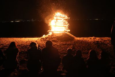 Silhouette people on beach against sky at night