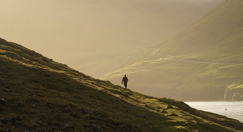 Rear view of man standing on mountain against sky