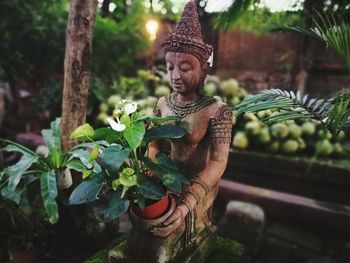 Close-up of buddha statue against trees
