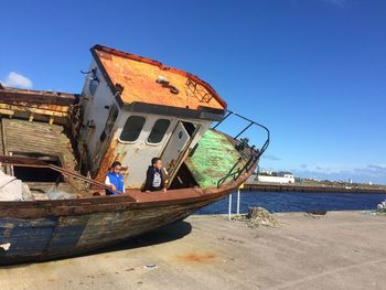 Abandoned boat moored on beach against clear blue sky
