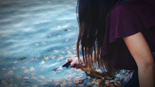 Midsection of woman touching water in lake