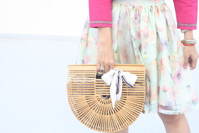 Midsection of woman holding umbrella standing by basket