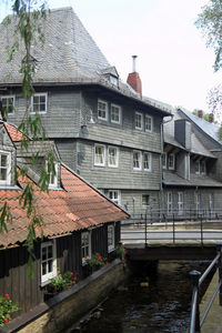 Houses by canal in city against clear sky