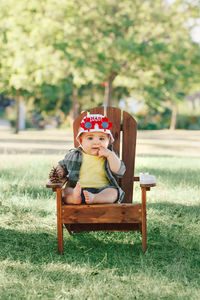 Portrait of cute baby boy sitting on seat in park