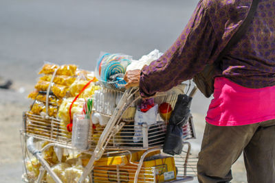 Midsection of woman pushing shopping cart while walking on street