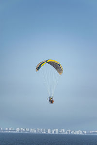 Low angle view of person paragliding against clear blue sky