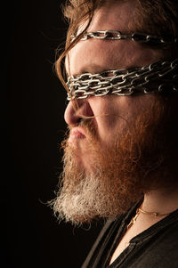 Close-up portrait of man wearing mask against black background