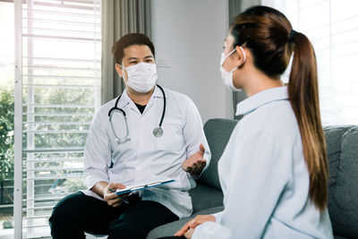 Doctor wearing mask talking with patient at clinic