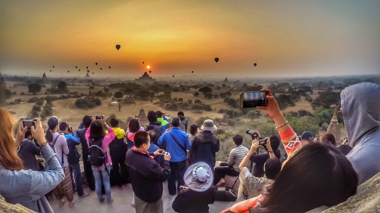 GROUP OF PEOPLE PHOTOGRAPHING IN CITY DURING SUNSET