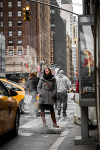 Smiling young woman looking up on street in city