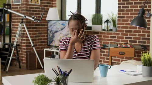 Side view of young woman using laptop while sitting on table