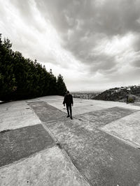 Rear view of man walking on footpath against sky