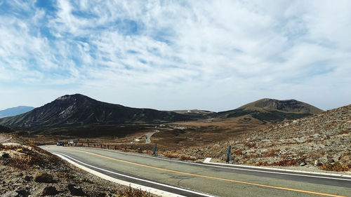 Road leading towards mountains against sky
