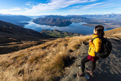 Side view of woman looking at mountains against sky