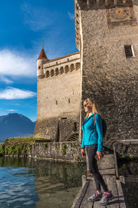 Adult blonde woman posing with a castle and lake geneva in the background