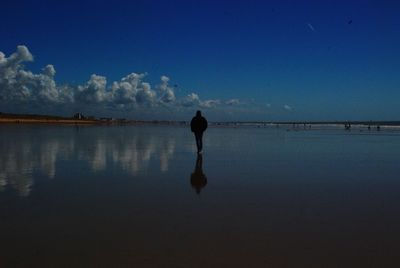 Rear view of man wading in sea against sky