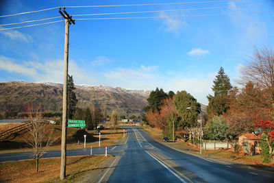 Road by trees against sky