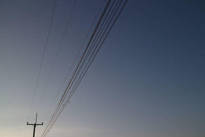 Low angle view of silhouette electricity pylon against sky