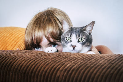 Portrait of boy with cat on sofa at home