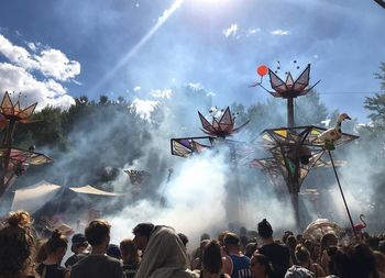 Group of people watching firework display against sky