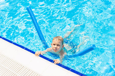 High angle portrait of smiling woman swimming in pool