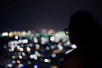 Close-up of woman looking at illuminated city