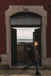 Blurred motion of woman walking by building in city