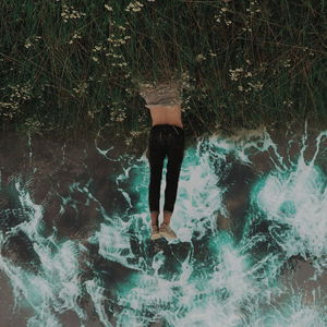 Low section of woman standing in swimming pool